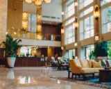 Eleganckie lobby hotelu 10 gwiazdkowego z marmurową podłogą, wygodnymi sofami i bujną roślinnością.