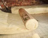 Rouleau de laine de verre posé sur un film pare-vapeur dans un grenier. Attention, la laine de verre peut être dangereuse si mal manipulée.