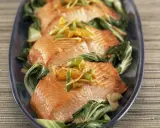 Saftiger Lachs mit Mangold, garniert mit Ingwer und Frühlingszwiebeln, auf einem dunkelblauen Teller serviert.