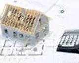 Maquette de maison sur des plans, avec une calculatrice. Un indice ICC pour estimer le coût de construction.