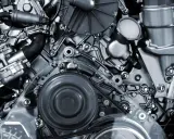 Detalle de un motor de cuatro tiempos, con correas, poleas y componentes metálicos pulidos.