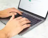 Dłonie piszą na laptopie. Może to być praca dla agencji copywriterskich, tworzenie treści lub analiza danych.