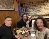Ambiance chaleureuse dans la taverne médiévale Paris. Quatre amis partagent un repas convivial, entre rires et dégustations.