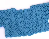 Bolero crochet azul con un delicado patrón de escamas y borde ondulado.