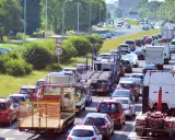 Korek na drodze, sznur samochodów i ciężarówek. Widać znak ograniczenia prędkości do 70. Może to być sytuacja wymagająca polisa car.