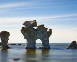 Raukar i havet vid Fårö, Gotland. En fantastisk vy att se på Gotland, med stenformationer som reser sig ur det blå vattnet under en molnig himmel.
