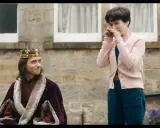 Un re con la corona e la pelliccia, forse il protagonista di "the lost king film", guarda una donna che ride con le mani sul viso.