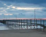 Molo di Rimini Rivazzurra al tramonto, con cielo nuvoloso e mare calmo.