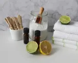 Słoik z sodą oczyszczoną, buteleczki z olejkami, cytryna, limonka i klamerki do prania. Naturalne środki czystości.