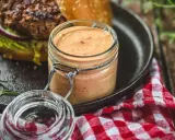 Leckere, cremige Sauce im Glas, perfekt zum schnelle Burger Sauce selber machen. Dazu ein saftiger Burger auf einem Gusseisen-Teller.