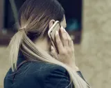 Kobieta rozmawia przez telefon, być może dowiadując się o **siłę wyższą kodeks pracy**.