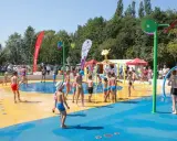 Dzieci bawią się na wodnym placu zabaw, jednej z atrakcji dla dzieci w Katowicach. Woda tryska z kolorowych elementów, tworząc radosną atmosferę.