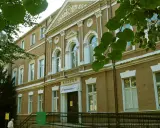 Fasada muzeum w Zielonej Górze, z napisem "MUZEUM". W pobliżu drzewa i ławka.