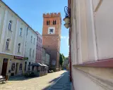 Krzywa wieża w Ząbkowicach Śląskich, ceglana, z zegarem, góruje nad brukowanym rynkiem.