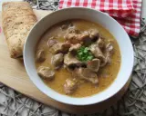 Aromaticzny gulasz wieprzowy w kremowym sosie, udekorowany natką pietruszki, podany z chrupiącym pieczywem.