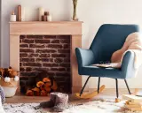 Un fauteuil bleu confortable invite à la détente près d'une cheminée en briques, créant un coin cheminée cocooning parfait pour lire.