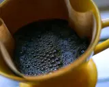 Heißer Kaffee mit Schaum in einer gelben Tasse. Ein Muntermacher, der den Unterschied zwischen Teein und Koffein verdeutlicht.