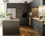 Cuisine gris anthracite avec un mur en briques apparentes. Un îlot central et des meubles sombres créent une ambiance moderne.