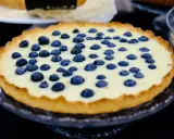 Pyszna tarta z borówkami na kremowym nadzieniu, ozdobiona świeżymi owocami. Idealna na deser.