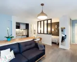 Aménagement studio 30m2 : salon cosy, cuisine moderne, chambre séparée par verrière, et coin repas.