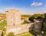 Il castello di Sarteano domina il borgo con le sue mura antiche e torri imponenti, circondato dal verde della campagna toscana.
