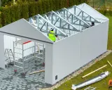 Budowa garażu w toku. Pracownicy montują konstrukcję dachu. Może to być kara za postawienie blaszaka bez zgłoszenia, jeśli nielegalnie.