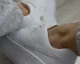 Białe sneakersy z szarym swetrem. Dowiedz się, jak zabezpieczyć białe buty, by długo wyglądały jak nowe.