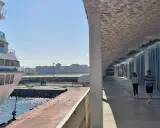 Una nave da crociera attracca nel porto di Leixões, Portogallo. Due persone passeggiano sotto una moderna tettoia con un soffitto decorato.