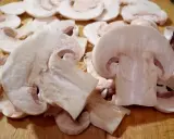 Pokrojone pieczarki na desce. Czy można jeść surowe pieczarki? Tak, te białe są gotowe do spożycia na surowo.
