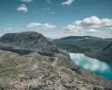 Piękny krajobraz Norwegii, gdzie nie robić nic, tylko podziwiać. Grupa turystów wędruje po skalistym szlaku nad turkusowym jeziorem.