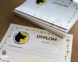 Stos dyplomów na satynowym papierze z motywem psich łapek i kości. Idealne dla psich przedszkoli i szkółek.