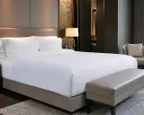 Cama de hotel con sábanas blancas impecables. ¿De qué marca son los colchones de los hoteles? Este lujoso dormitorio invita al descanso.