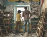 Pareja evalúa cuánto cuesta reformar una casa, rodeada de escaleras y materiales de construcción en una habitación en ruinas.