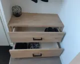 Meuble à chaussures fait maison en bois clair, avec deux tiroirs ouverts contenant des bottes et des baskets.