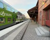Grönt tåg med texten "LaVaunu" står vid en tegelbyggnad. Kanske är det ett tåg till Haparanda som väntar på passagerare.