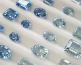 Collezione di acquamarine con taglio smeraldo e altre forme, che brillano su un morbido sfondo bianco.