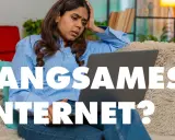 Verzweifelte Frau fragt sich: "Warum ist mein Internet so langsam?" Sie sitzt frustriert vor ihrem Laptop.