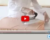Manos planchando tela de viscosa con vapor en una tabla de planchar.