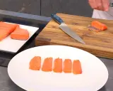 Filetes de salmón marinado listos para servir. Un cuchillo y una tabla de cortar de madera sugieren preparación.