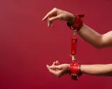 Czerwone kajdanki, symbol bdsm skrót, na nadgarstkach. Dłonie wyciągnięte w geście.