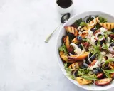 Salat mit Nektarinen, Blaubeeren, Ziegenkäse und Pekannüssen, garniert mit roten Zwiebelringen.