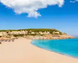 Traumhafter **Spanien Strand** mit feinem Sand, türkisfarbenem Meer und Hotels auf einem Hügel.