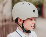 Chłopiec w beżowym kasku rowerowym, rozmiar 52-56, idealny dla dziecka w wieku około 5-8 lat.
