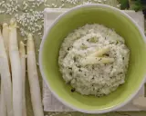 Delicioso risotto de espárragos cremoso, adornado con espárragos blancos y perejil picado. Acompañado de espárragos frescos y trozos de queso parmesano.