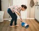 Mujer barriendo el suelo con escoba y recogedor, aplicando trucos de limpieza para mantener el hogar impecable.