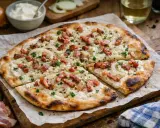 Une délicieuse flammekueche, garnie d'oignons et de lardons, prête à être dégustée. Parfait pour une recette facile et savoureuse.