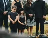 Dziecko na pogrzebie, smutek i zaduma. Wśród dorosłych, w czerni, dziecięce twarze wyrażają powagę chwili, być może nie rozumiejąc jeszcze wszystkich przesądów związanych z tym wydarzeniem.