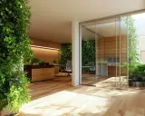 Oficina moderna con abundante vegetación interior. Una gran planta verde domina el primer plano. Al fondo, una **ventana sin marco detalle** permite ver un patio interior con más plantas.