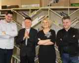 Jacek Ostrowski z książkami w kolejności. Grupa osób pozuje na tle regałów z książkami.