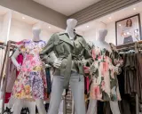 Manekiny w sukienkach w kwiaty i zielonej kurtce. To styl marki Scotch & Soda, znanej z kolorowych, letnich ubrań.